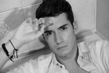 Sigara içerken küvette poz veren beyaz gömlekli güzel çocuk.