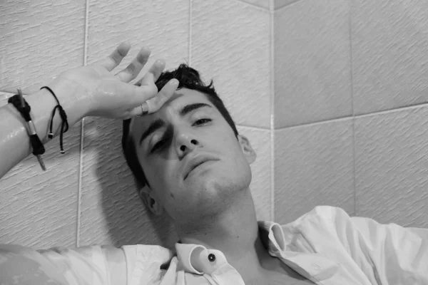 一个漂亮的男孩 身穿白衬衫 在浴缸里摆姿势吸烟 — 图库照片