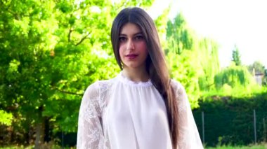 Güzel, siyah saçlı, uzun saçlı, gülümseyen ve saçlarını düzleştiren bir İtalyan kızı.