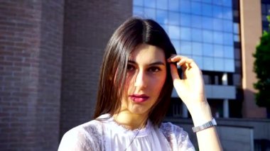 Güzel, siyah saçlı, uzun saçlı, gülümseyen ve saçlarını düzleştiren bir İtalyan kızı.