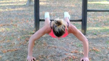 Güzel esmer İtalyan kız halka açık parkta şınav çekiyor ve egzersiz yapıyor.