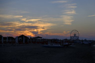 Rini plajı, parlak renkleri ve deniz panoramik tekerleği olan güzel bir gün batımı.