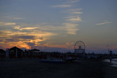 Rini plajı, parlak renkleri ve deniz panoramik tekerleği olan güzel bir gün batımı.