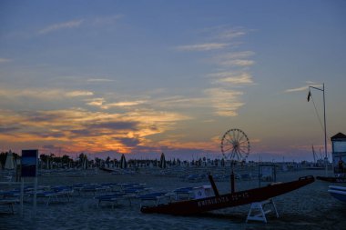 Rini plajı, parlak renkleri ve deniz panoramik tekerleği olan güzel bir gün batımı.