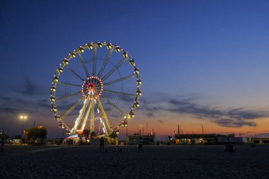 Rini plajı, parlak renkleri ve deniz panoramik tekerleği olan güzel bir gün batımı.