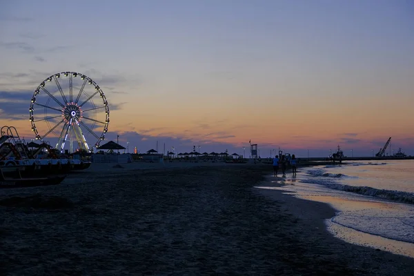 Playa rimini hermosa puesta de sol con colores brillantes y la rueda panorámica del mar — Foto de Stock