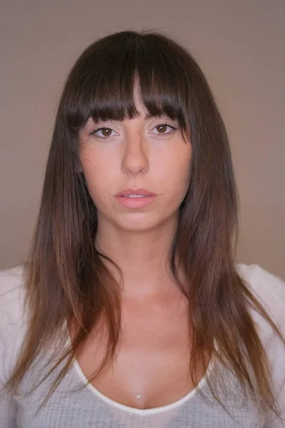 Πορτρέτο του όμορφη μελαχρινή κοπέλα με χαμηλά κομμένα μακριά μαλλιά και λευκό t-shirt σε έγχρωμη φωτογραφία — Φωτογραφία Αρχείου