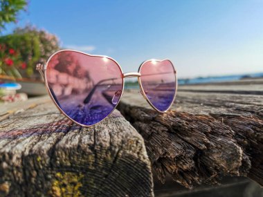 Tahta iskelede güneş ve Garda Gölü 'nün yansıması olan kalp şeklinde güneş gözlükleri.