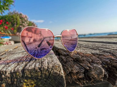 Tahta iskelede güneş ve Garda Gölü 'nün yansıması olan kalp şeklinde güneş gözlükleri.
