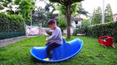 Güzel çocuk covid 19 salgını sırasında bahçede mavi salıncakla oynuyor.