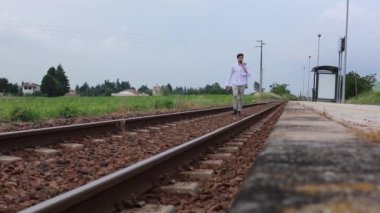 Güzel İtalyan çocuk tren raylarında çaresizce yürüyor.