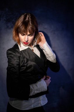 Kısa saçlı güzel İtalyan bir kız. Stüdyoda seksi iç çamaşırlarıyla renkli ışıklarla poz veriyor.