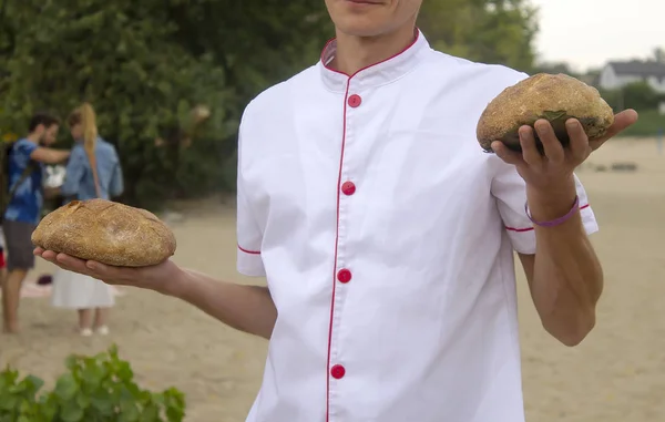 Satıcının elinde bir somun ekmek. Genç bir adam panayırda ekmek reklamı yapıyor ve satıyor..