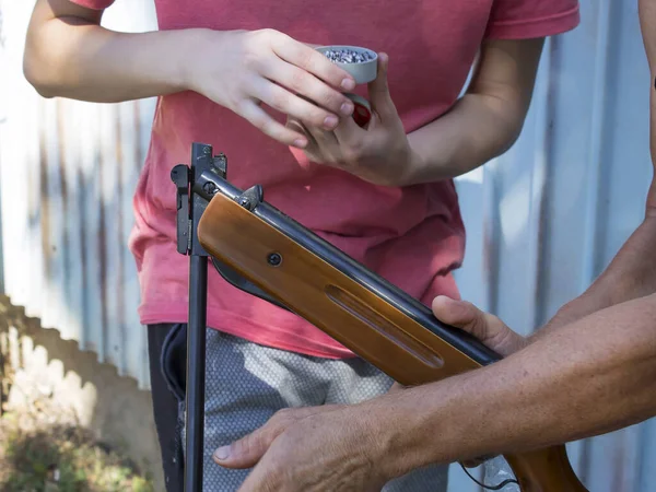 İki adam havalı tüfeği metal mermilerle dolduruyor..