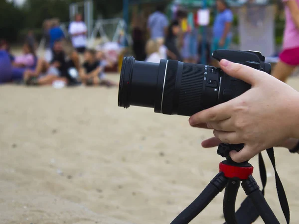 这个女摄影师在一个城市海滩上的河岸上做了一个故事 他的相机在三脚架上 — 图库照片