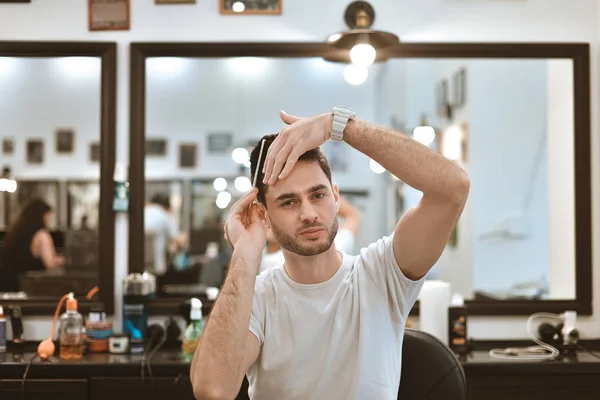 El tipo está peinando su propio cabello. Peinado en la barbercosh . — Foto de Stock