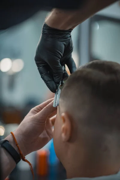 Forma ideal das barbas e cortes de cabelo na barbearia. Barbeiro sugere o contorno com uma navalha. Cuidado corporal dos homens. Foco suave . — Fotografia de Stock