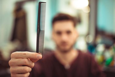 Bir tarak uzanmış elinde tutan bir adam. Yumuşak odak.