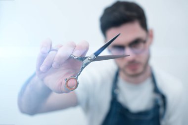 Onun elinde Clippers araçlar olan adam. Genç Kuaför makası görünüyor. Ellerini üstüne odaklanmak.
