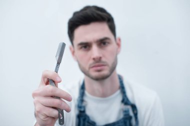 Kuaför Salonu. Kuaför Close-Up sakalını tıraş için jilet tutar. Ellerini üstüne odaklanmak.