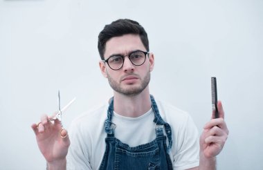 Kuaför Saç kesimi için hazırlanıyor. Sakallı adam beyaz duvarlar yerinde duruyor onun elinde makas tutan.