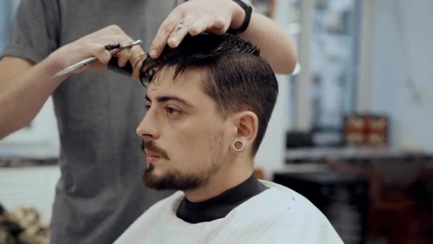 Barbeiro corta um homem num salão de beleza . — Vídeo de Stock