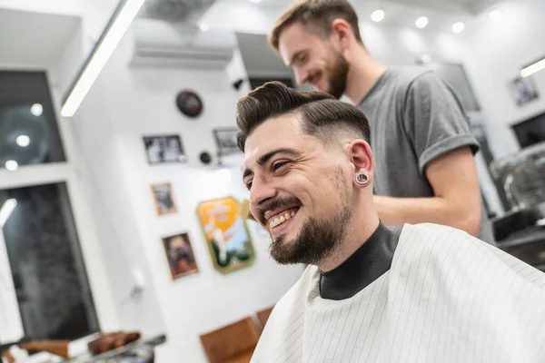 Customer smiling in barber shop with barber. Fun barber.