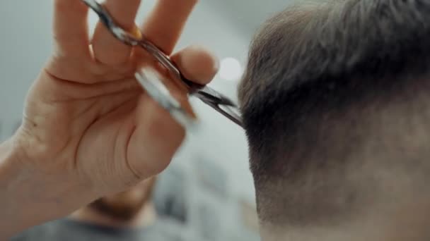 Мужчина парикмахер стрижет клиента в парикмахерской — стоковое видео