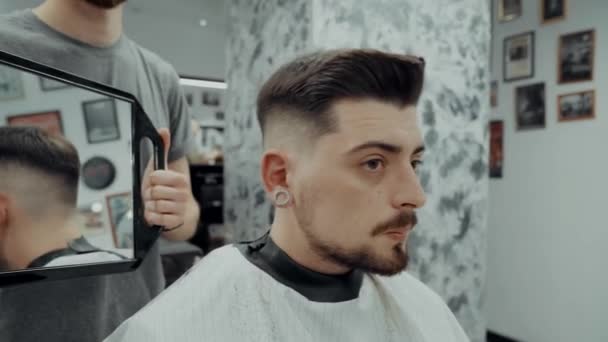 Der Kunde schaut den Haarschnitt durch den Spiegel an. — Stockvideo