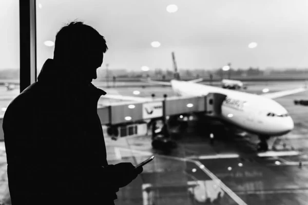 Silhouette of a man at the airport. Man waiting for his flight. Black and white photo. — Stock Photo, Image