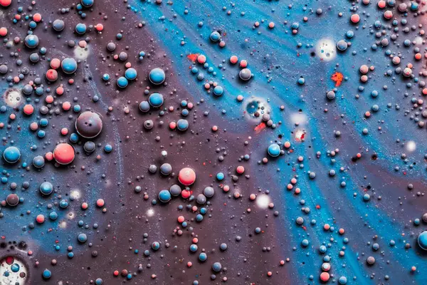Färgdroppar flyter i olja och vatten över en färgglad underjordiska med oljemålning effekt. — Stockfoto
