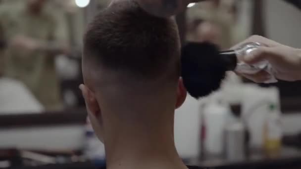 Completando un corte de pelo. Peluquero limpia al cliente del cabello . — Vídeo de stock