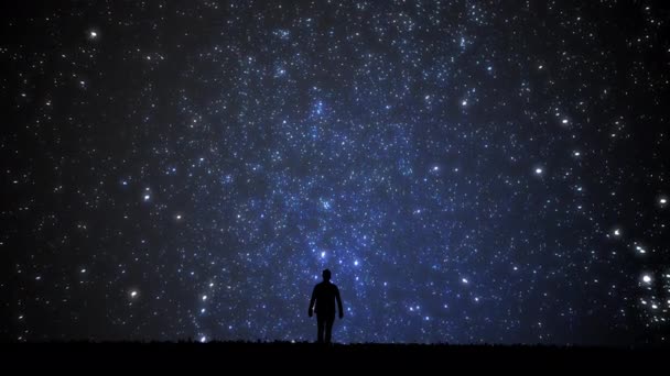 Adam yıldızlara bakıyor. Yıldızlı gökyüzüne bakan yalnız bir adam. Gece gökyüzü. — Stok video