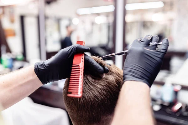 Mens haircut in a barbershop. Client and barber in anti-virus masks.