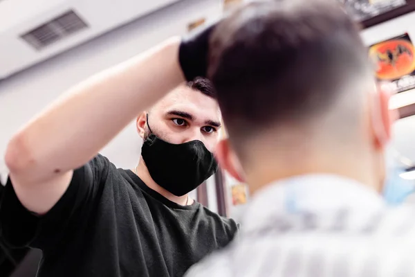 Чоловіча зачіска в перукарні. Клієнт і перукар в антивірусних масках . — стокове фото