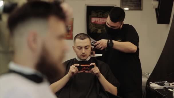 O barbeiro corta o cabelo aos clientes. Corte de cabelo dos homens em uma barbearia . — Vídeo de Stock