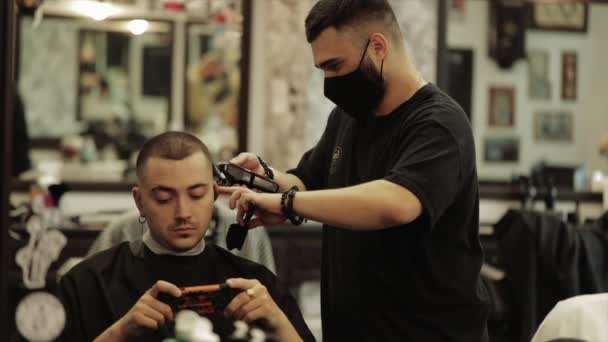 Barber cuts the clients hair. Mens haircut in a barbershop. — Stock Video