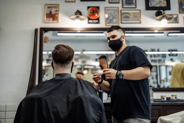 Barbiere fa un taglio di capelli e acconciatura in un barbiere, salone di bellezza. — Foto Stock