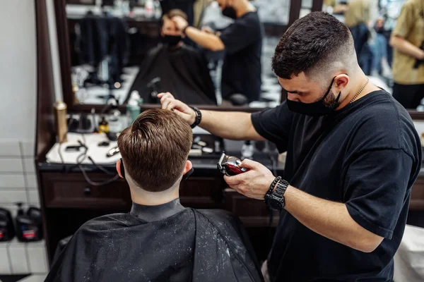 Barber makes a haircut and hair styling in a barbershop, beauty salon. — Stock Photo, Image