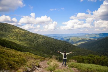 Sırt çantası ayakta bir kaya üzerinde olan mutlu kadın