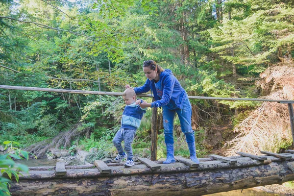 Пішохідна родина перетинає дерев'яний міст — стокове фото