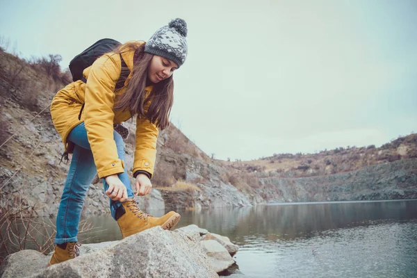 Donna in stivali e jeans cammina lungo il lago — Foto Stock