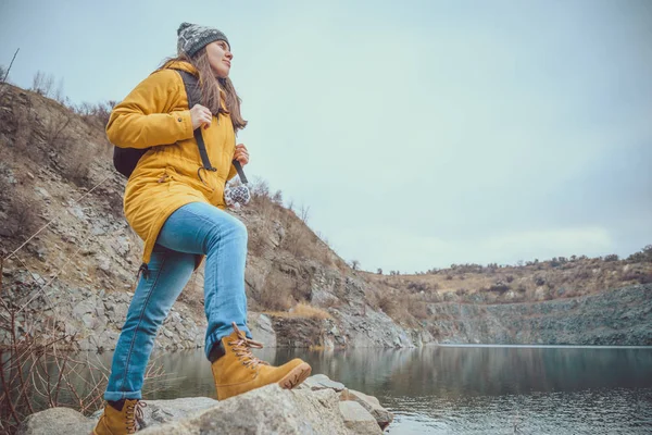 Donna in stivali e jeans cammina lungo il lago — Foto Stock