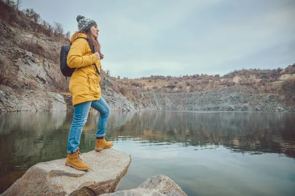 Donna in stivali e jeans cammina lungo il lago — Foto Stock