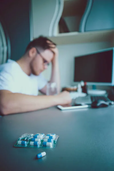 Hombre sentado y mirando píldoras — Foto de Stock