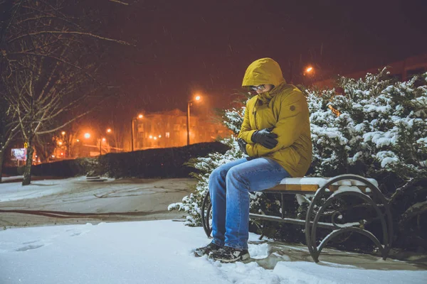 Hombre sentado en un banco en la fría noche de invierno — Foto de Stock