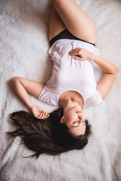 Ung kvinna som ganska mörkt hår i sängen — Stockfoto