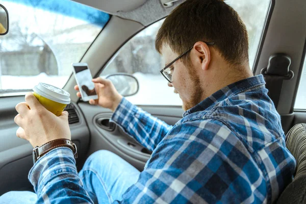 Мужчина ищет информацию в телефоне, сидя в машине — стоковое фото