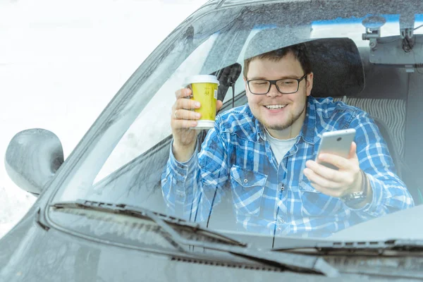 man looking info in phone while sitting in car