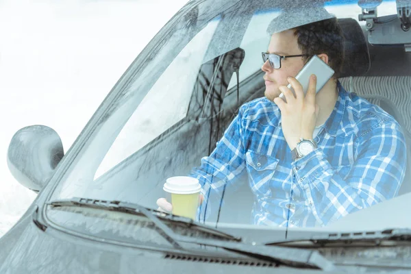 man looking info in phone while sitting in car